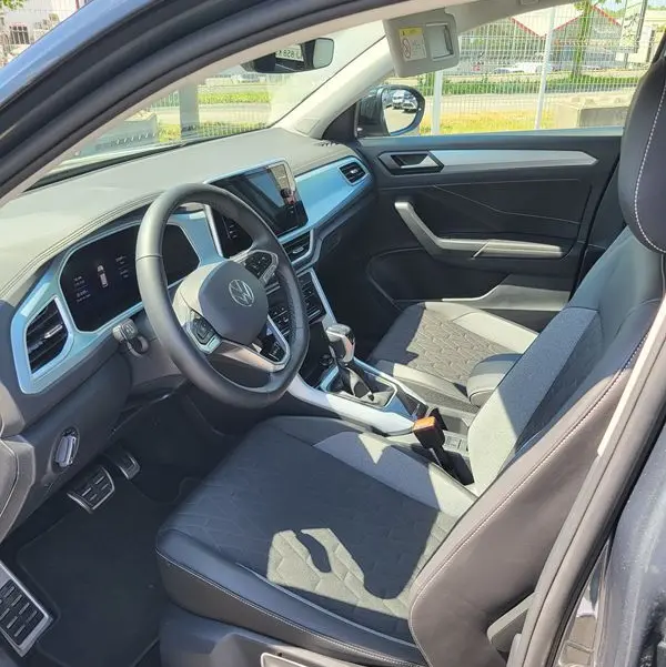Intérieur côté conducteur du Volkswagen T-Roc gris Indium 2025, montrant tableau de bord et sièges tissu et cuir.