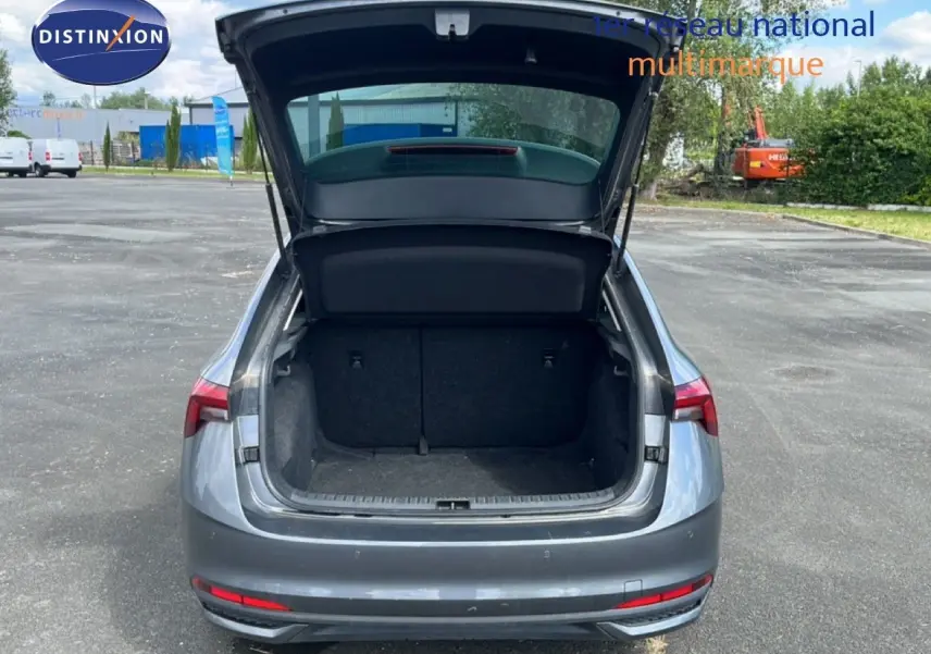 Vue arrière d'une Skoda Scala gris graphite métal 2025 avec coffre ouvert sur un parking extérieur.