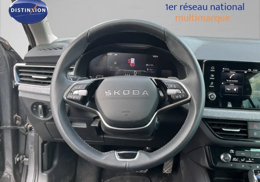 Vue intérieure centrée sur le volant cuir noir SKODA d'une Scala 2025, avec tableau de bord digital et écran tactile gris graphite.