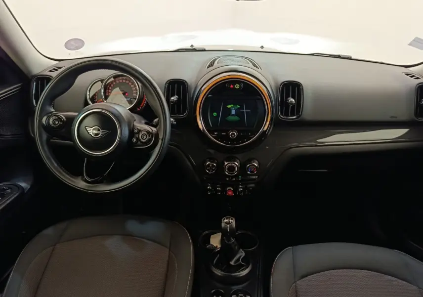 Vue intérieure avant du tableau de bord noir de la MINI Countryman Cooper 2019 avec volant cuir et écran central rond lumineux.