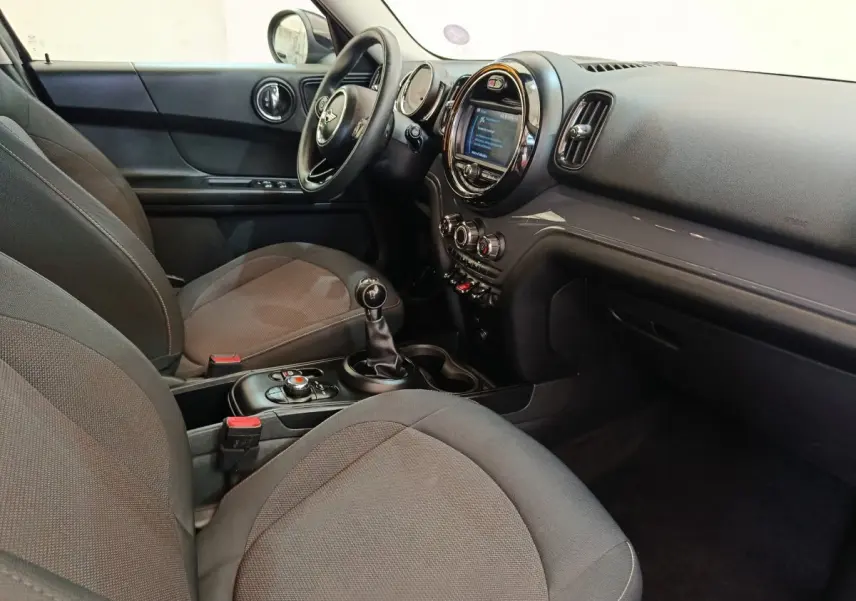 Intérieur avant droit du MINI Countryman noir 2019, tableau de bord avec écran central rond et boîte manuelle.
