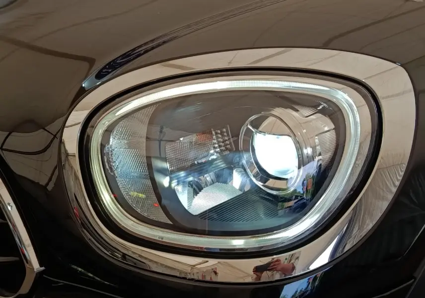 Gros plan sur le phare avant droit LED du MINI Countryman Cooper noir, soulignant son design moderne et lumineux.