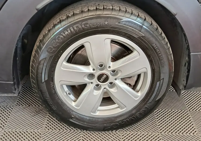 Gros plan sur la roue avant droite d'une MINI Countryman noire, mettant en valeur la jante argentée et le pneu Kumho.