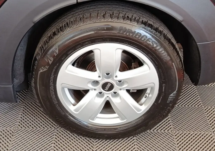 Gros plan sur la roue avant droite argentée d’une MINI Countryman noire, avec pneu Bridgestone visible.