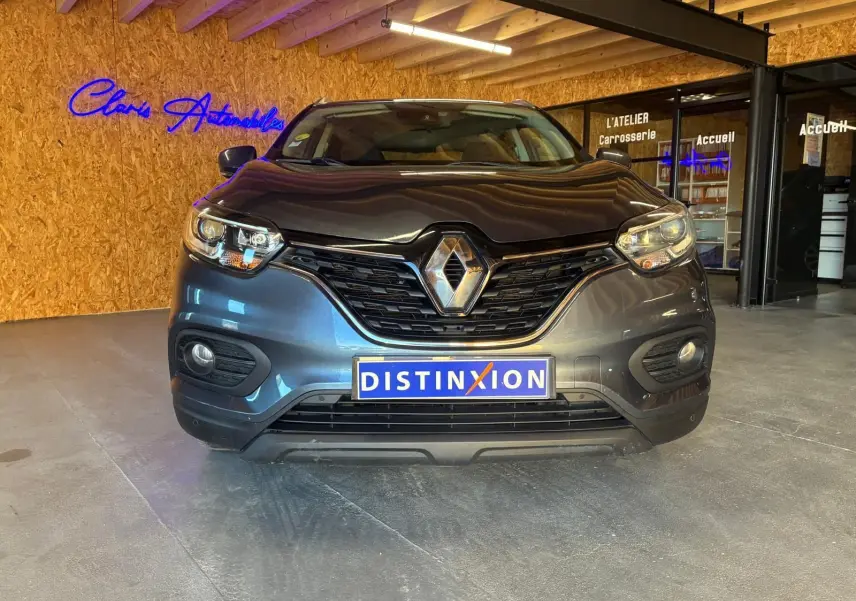 Vue frontale d'un Renault Kadjar gris 2019 avec calandre noire et logo chromé, en intérieur showroom.
