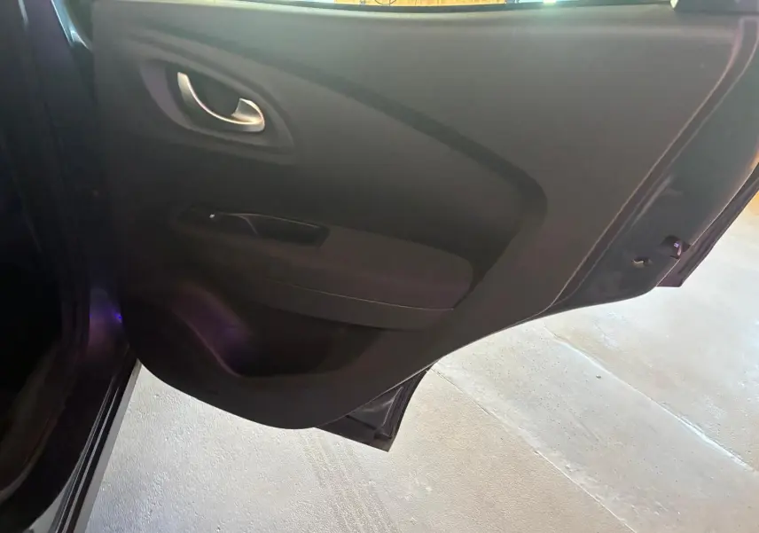 Vue intérieure de la porte arrière droite du Renault Kadjar gris, montrant la poignée et le panneau de porte en tissu noir.