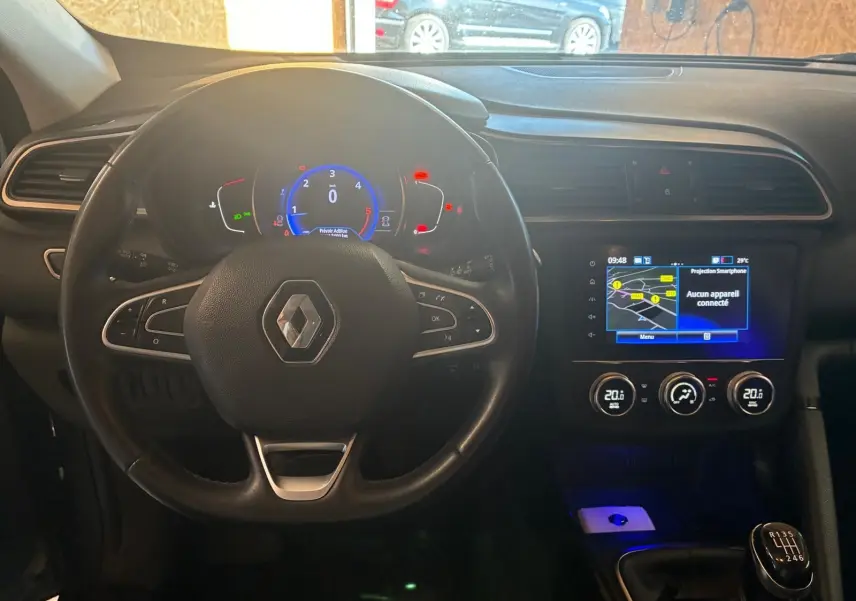 Vue intérieure centrée sur le volant Renault et le tableau de bord avec écran tactile et levier de vitesses manuel.