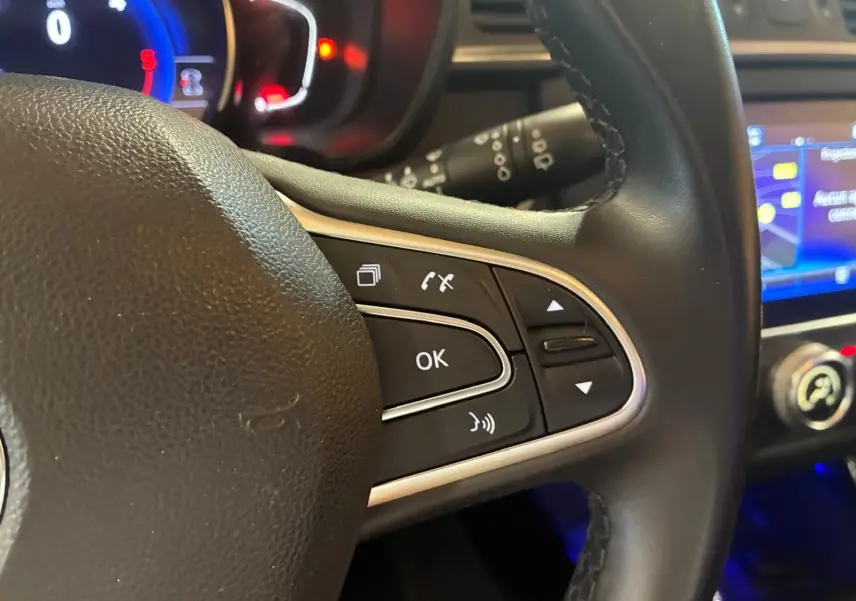 Gros plan sur la partie droite du volant noir du Renault Kadjar 2019 avec commandes multifonctions et tableau de bord éclairé.