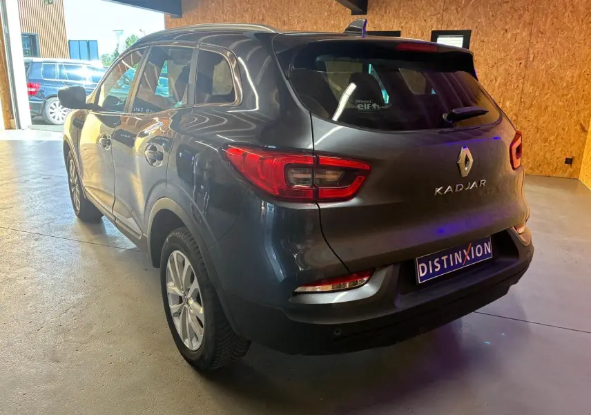 Vue 3/4 arrière droite d'un Renault Kadjar gris 2019 dans un garage avec éclairage naturel et artificiel.