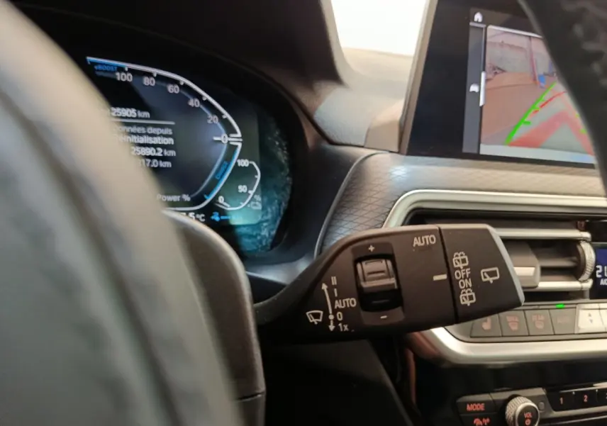 Gros plan sur le combiné d'instruments et la commande d'essuie-glace dans l'habitacle d'une BMW X3 blanche 2023.