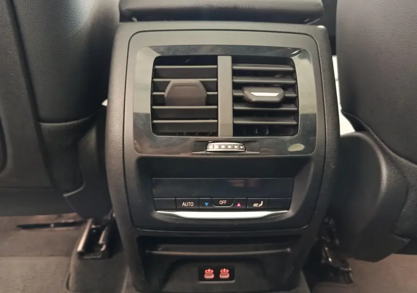Vue rapprochée de la console arrière noire avec bouches d’aération et commandes climatisation du BMW X3 blanc 2023.
