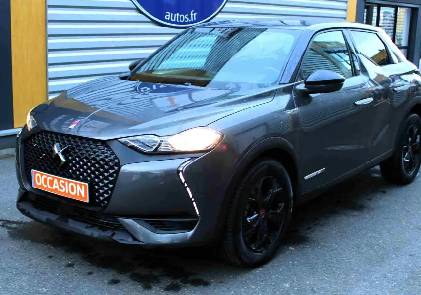 DS3 Crossback gris platinium métal en 3/4 avant droit, avec calandre noire et feux allumés, roues noires.