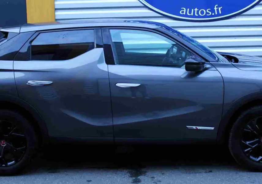 Vue de profil côté gauche d'un DS3 Crossback gris platinium métal avec jantes noires et lignes sculptées.
