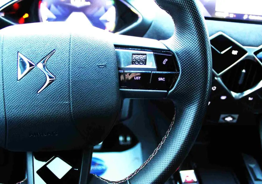 Gros plan sur le volant en cuir noir perforé du DS3 Crossback, avec logo DS et commandes intégrées.
