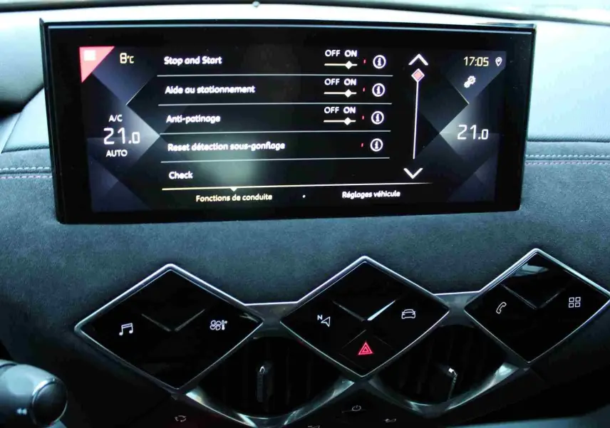 Vue rapprochée de l'écran tactile central et des commandes en losange du tableau de bord du DS3 Crossback gris platinium.