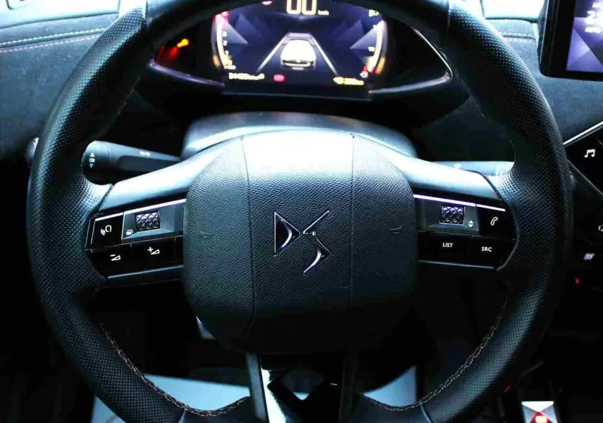 Vue rapprochée du volant en cuir noir du DS3 Crossback 2021 avec commandes intégrées et tableau de bord numérique.