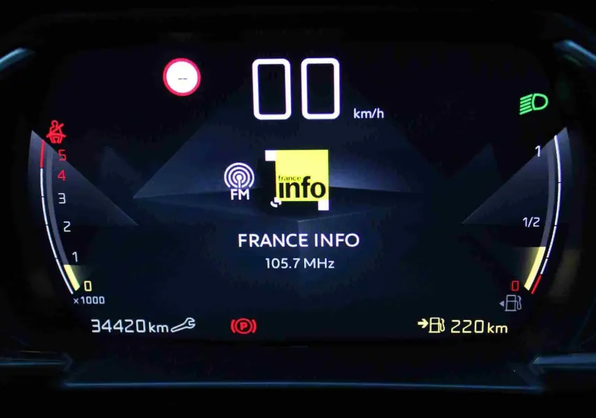 Tableau de bord numérique du DS3 Crossback gris platinium, affichant la radio France Info et la jauge de carburant.