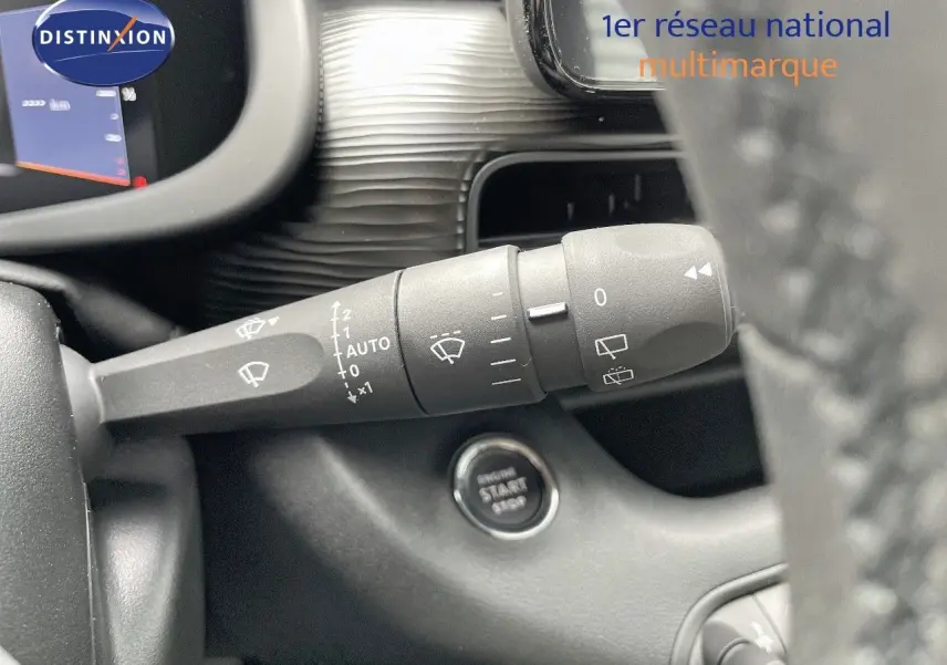 Gros plan sur la commande d'essuie-glace et le bouton start/stop du tableau de bord d'une Jeep Avenger blanc neige 2024.