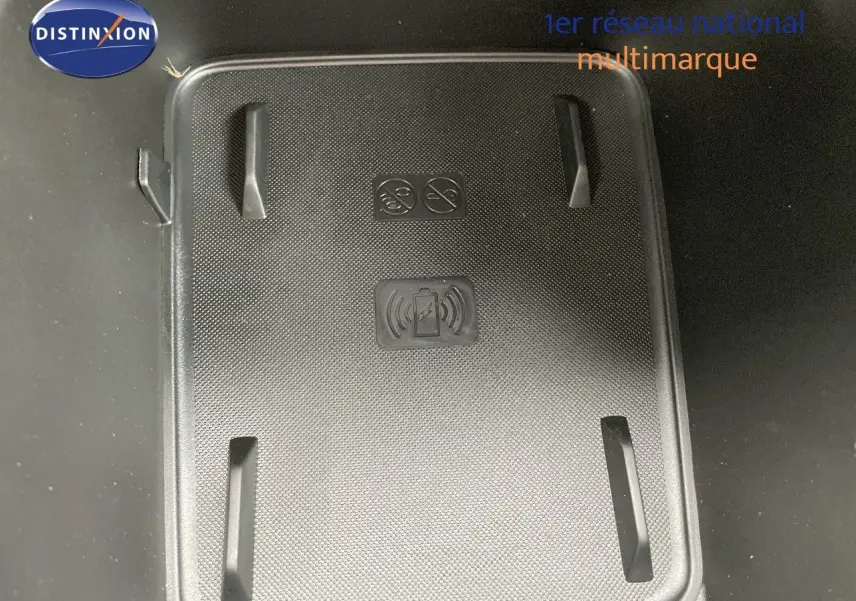 Surface de recharge sans fil noire dans l'habitacle du Jeep Avenger blanc neige, vue en plongée.