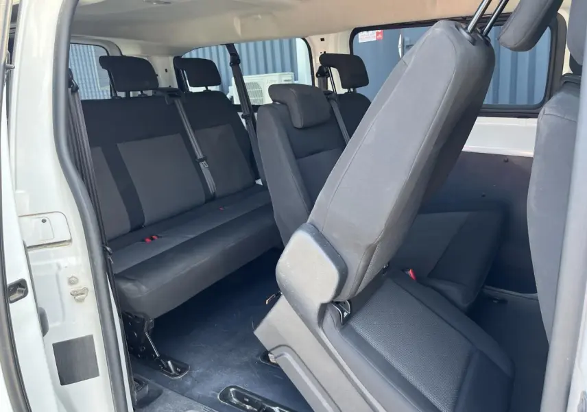 Vue intérieure côté droit du Toyota Proace Fourgon blanc 2021, montrant les sièges en tissu gris clair et la porte latérale ouverte.