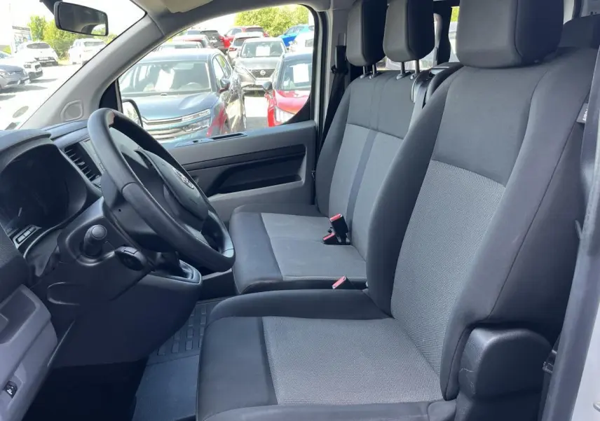 Vue intérieure côté conducteur du Toyota Proace Fourgon 2021, sièges tissu gris clair et tableau de bord noir.