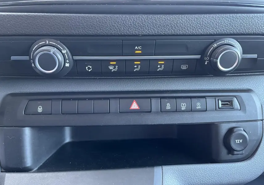 Tableau de bord noir du Toyota Proace Fourgon 2021 avec commandes climatisation et prise 12V visibles en gros plan.
