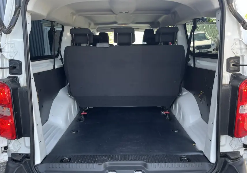 Vue arrière ouverte du Toyota Proace Fourgon blanc 2021, montrant l'espace de chargement et la banquette arrière noire.