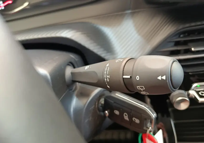 Gros plan sur la commande d’essuie-glace côté gauche du tableau de bord d’une Peugeot 208 blanche 2023.