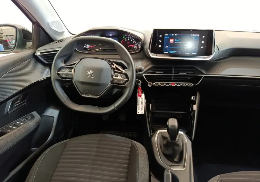 Vue intérieure avant centrée sur le volant cuir et la console centrale avec écran tactile de la Peugeot 208 PureTech 75 S&S Style.