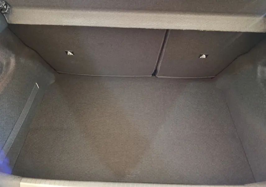 Coffre vide de la Peugeot 208 PureTech 75 S&S Style 2023, vue intérieure arrière avec revêtement gris foncé.