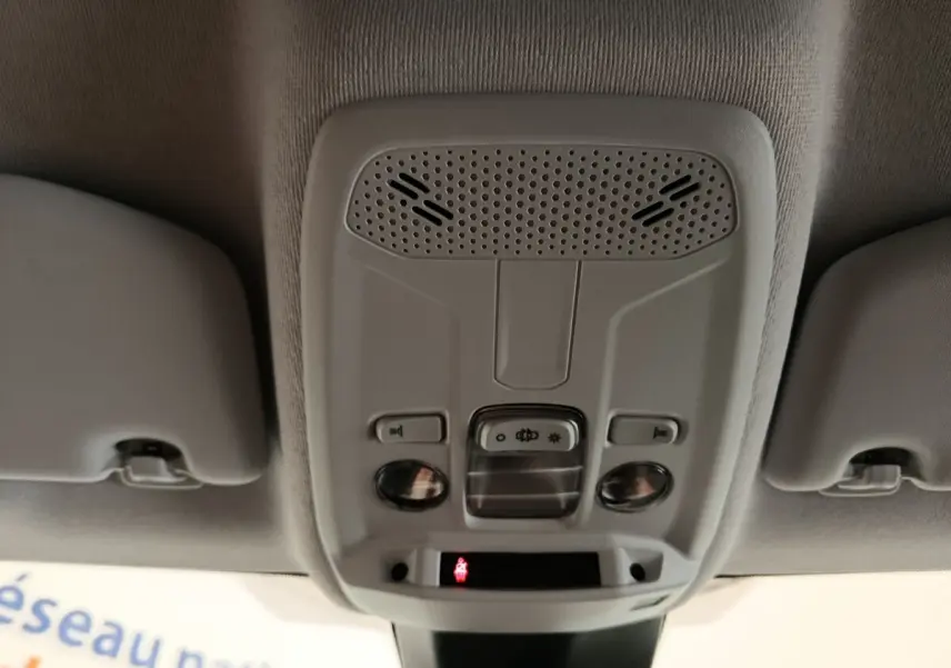 Plafonnier intérieur gris clair avec commandes d’éclairage et haut-parleurs, vue de dessous dans une Peugeot 208 blanche.