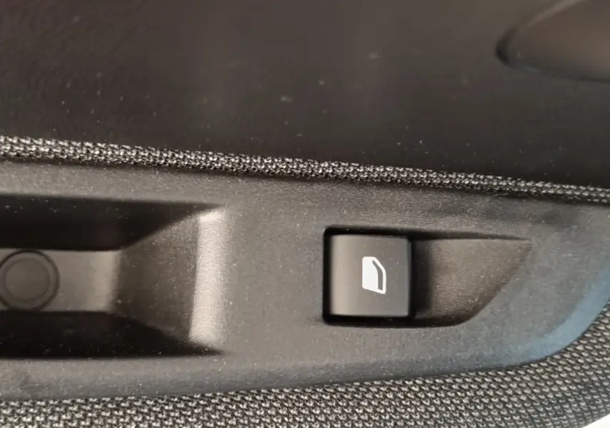 Gros plan sur le bouton d'ouverture de trappe à carburant noir dans l'habitacle d'une Peugeot 208 blanche 2023.