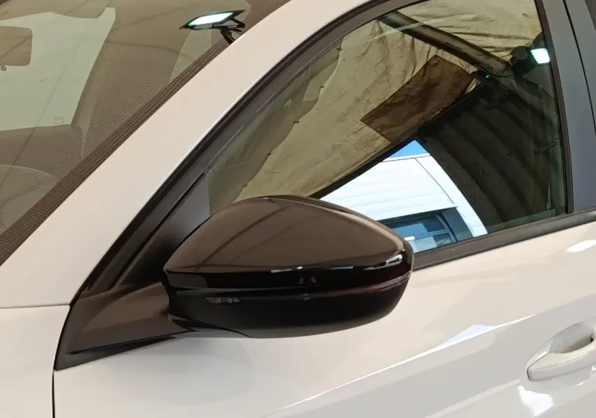 Rétroviseur noir brillant côté conducteur d'une Peugeot 208 blanche PureTech 75 S&S Style 2023, vue latérale rapprochée.
