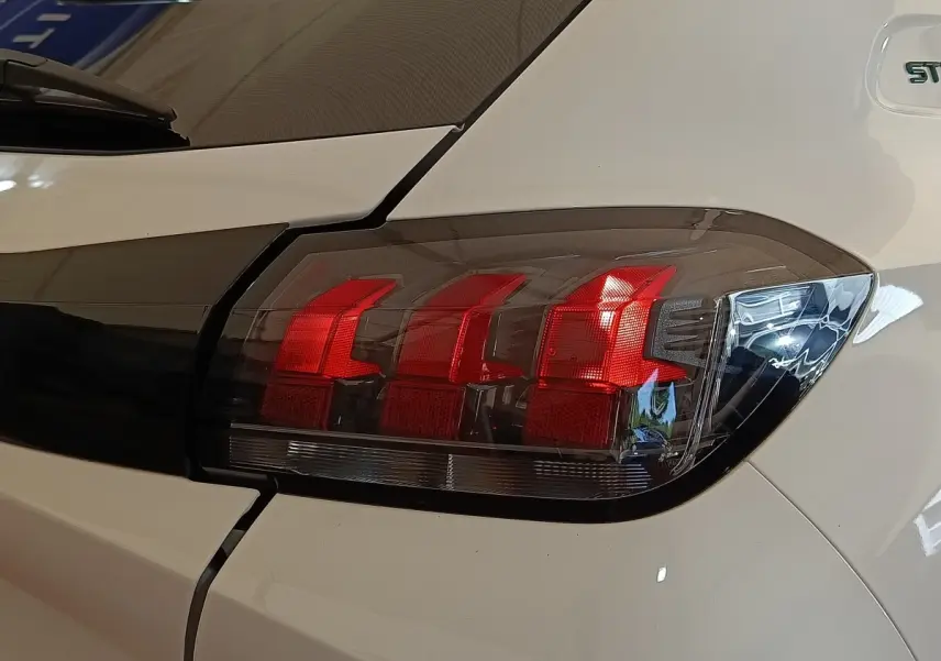 Gros plan sur le feu arrière droit rouge et noir de la Peugeot 208 blanche PureTech 75 S&S Style 2023.
