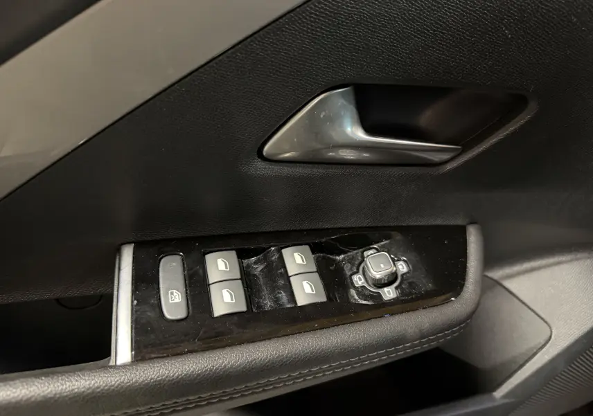 Gros plan sur la commande des vitres et rétroviseurs côté conducteur de l'Opel Astra gris 2024.