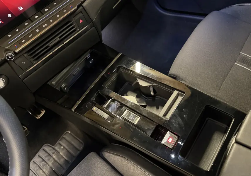 Vue intérieure rapprochée de la console centrale noire brillante de l’Opel Astra 2024 avec pédalier alu et sièges gris.