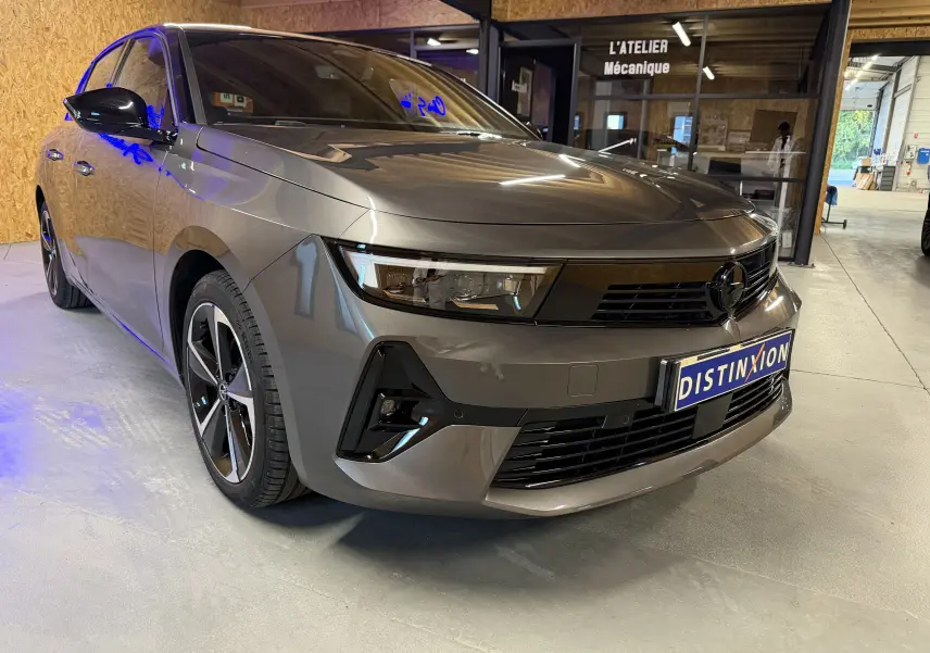 Opel Astra 1.5D 130 BVA8 gris métallisé vue 3/4 avant droit avec jantes alliage 17'' et calandre noire.