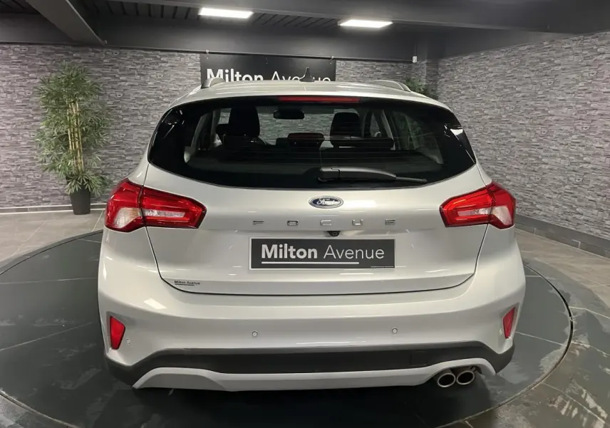 Vue arrière d'une Ford Focus gris clair avec double sortie d'échappement et feux arrière rouges dans un showroom.