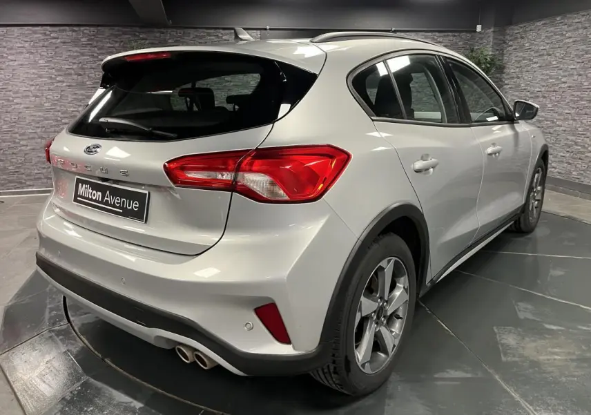 Vue 3/4 arrière droite d'une Ford Focus gris lunaire 2021 avec double sortie d'échappement et jantes alliage 17 pouces.