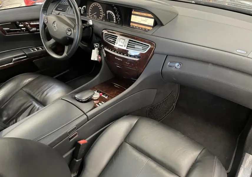 Vue intérieure côté conducteur de la Mercedes Classe CL 500 4-Matic 2009 avec cuir noir et console bois.