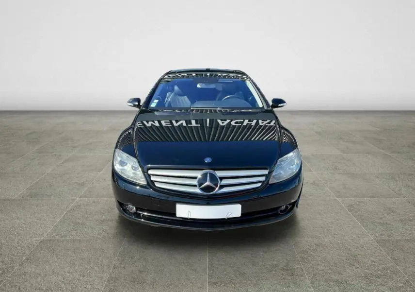 Vue frontale d'une Mercedes Classe CL 500 4-Matic noire avec calandre chromée et phares bi-xénon allumés.