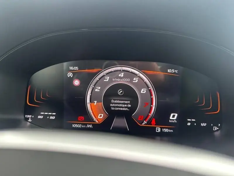 Vue rapprochée du tableau de bord numérique du SEAT Arona 2025, affichage tachymètre et informations de conduite en orange.