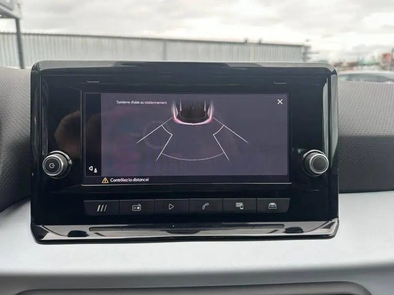 Écran tactile central du tableau de bord du SEAT Arona 2025 affichant l'aide au stationnement, entouré de commandes noires.