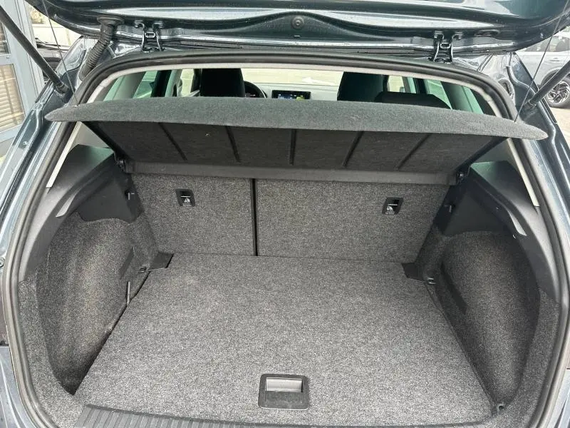 Coffre ouvert vu de l'arrière d'un SEAT Arona 2025 gris Magnétique Métal avec toit noir, montrant l'espace de chargement et la tablette cache-bagages.