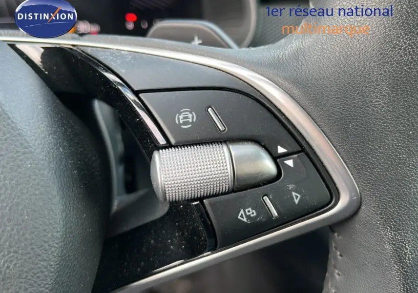 Gros plan sur les commandes multifonctions en plastique noir et chrome du volant d’une Skoda Scala gris graphite.