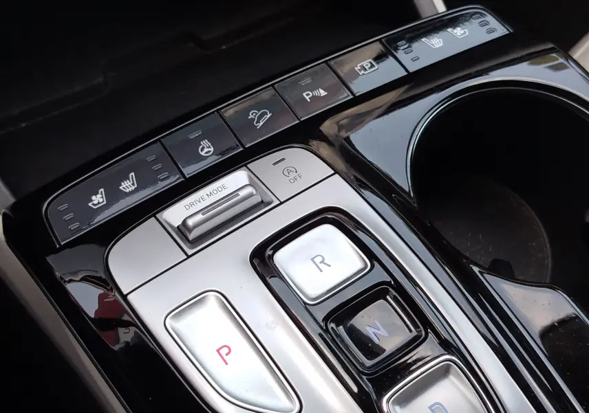 Gros plan sur la console centrale noire et argentée du Hyundai Tucson 2021, avec boutons de boîte auto et commandes de sièges chauffants.