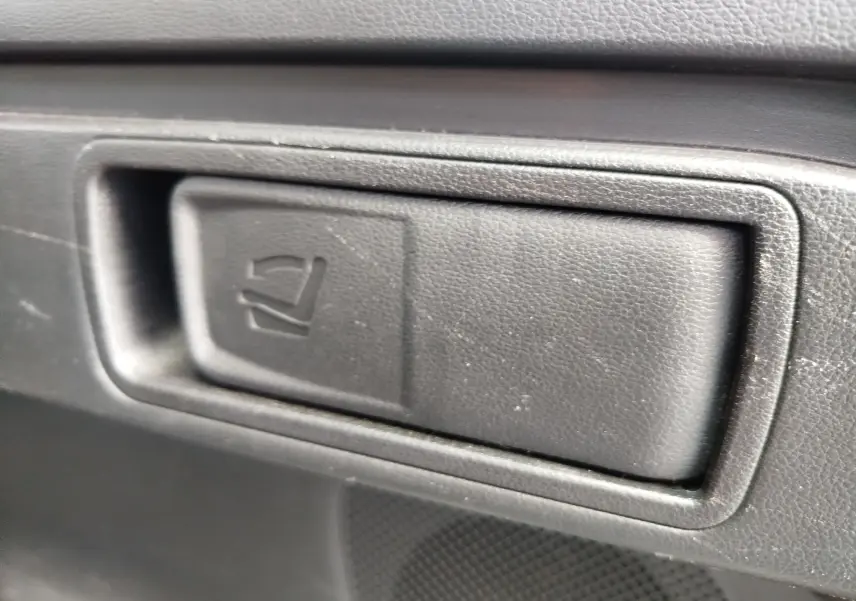 Gros plan sur le bouton de rabattement des sièges arrière en plastique noir à l'intérieur du Hyundai Tucson 2021 Teal Blue Métal.