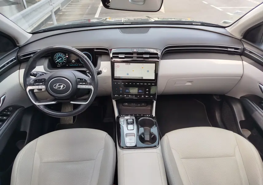 Vue intérieure frontale du Hyundai Tucson 2021, tableau de bord noir et beige avec écran tactile central et volant multifonction.