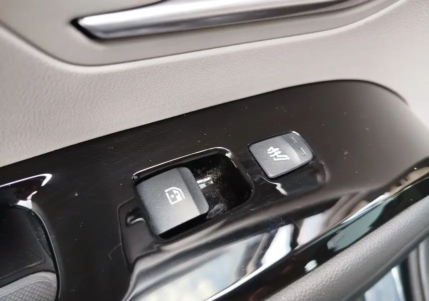 Gros plan sur les boutons de commande de la vitre et siège chauffant côté conducteur du Hyundai Tucson 2021 en Teal Blue Métal.