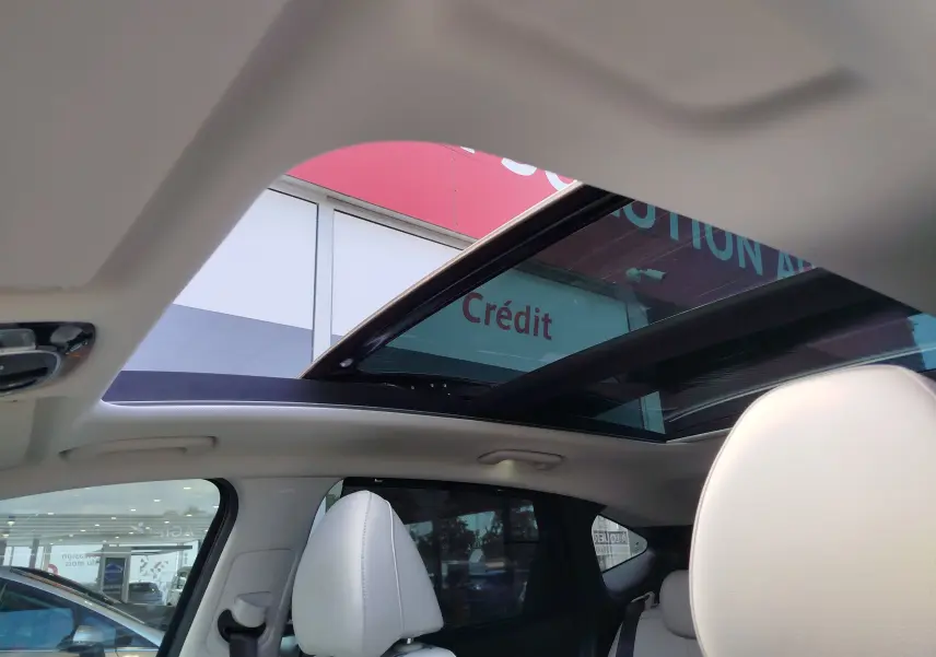 Vue intérieure du Hyundai Tucson 2021 avec toit panoramique ouvert et sièges en cuir clair visibles.